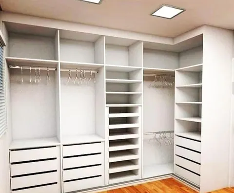 Closet branco de canto com cabideiros, nichos e gavetas