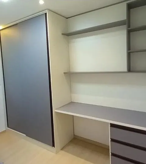 Closet com porta de correr cinza e bancada de escritório com prateleiras
